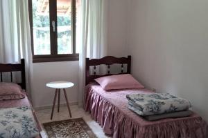 1 dormitorio con 2 camas, mesa y ventana en Sítio Som das Águas, en Benedito Novo