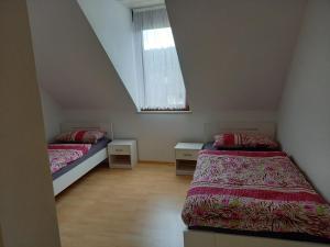 two beds in a small room with a window at Ferienwohnung Enz, 3 OG. in Pforzheim