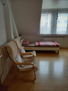 プフォルツハイムにあるFerienwohnung Enz, 3 OG.の椅子とベッド、窓が備わる客室です。