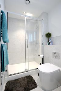 a white bathroom with a shower and a toilet at Ground Floor One Bedroom Flat Centre of Woking with Off Street Parking in Woking