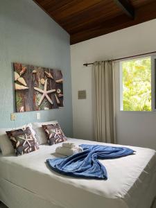 uma cama com um cobertor azul com uma janela em Pousada Estrela do Mar em Maresias