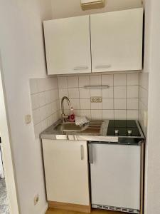 a small kitchen with white cabinets and a sink at Gemütliches Appartement nahe Universitätsklinik in Magdeburg