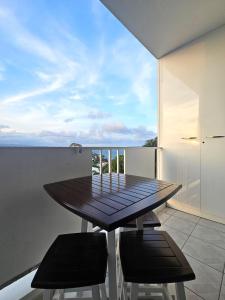 un tavolo e sedie su un balcone con vista sull'oceano di Sweet Crépuscule - Studio avec Vue Mer Imprenable & Piscine a Les Trois-Îlets
