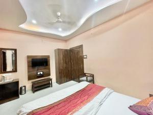 a bedroom with a bed and a flat screen tv at HOTEL NEEL GAGAN ! VARANASI fully-Air-Conditioned hotel at prime location, near Kashi Vishwanath Temple, and Ganga ghat in Varanasi