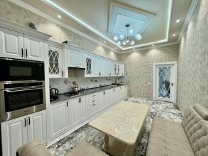 une cuisine avec des placards blancs et une table. dans l'établissement Samarkand luxury apartament #8, à Samarcande