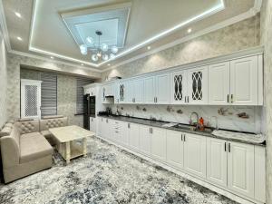 cocina con armarios blancos y mesa en Samarkand luxury apartament #8 en Samarcanda