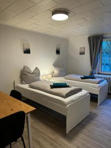 two beds in a room with a table at 5-Bett Wohnung im Boardinghaus Elisabeth in Dinslaken