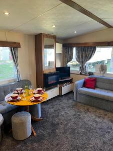 een woonkamer met een tafel en een televisie bij Sea View, Thorness Bay in Porchfield