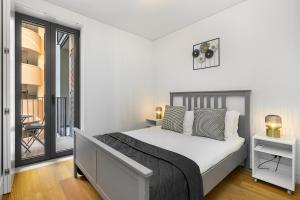 a white bedroom with a bed and a balcony at WHome Urban Elegance: A Modern Haven in Lisbon's Heart in Lisbon