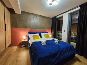 a bedroom with a bed with blue sheets and yellow pillows at Apartament RS6 in Zakopane