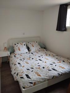 ein Schlafzimmer mit einem Bett mit einer weißen Bettdecke in der Unterkunft Appartement Cosy avec extérieur in Saint-Privat-des-Vieux