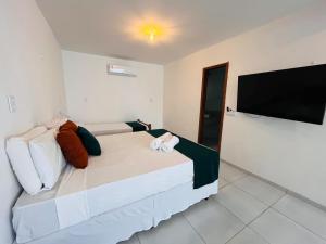 a bedroom with a large bed and a flat screen tv at Pousada Enero in Maragogi