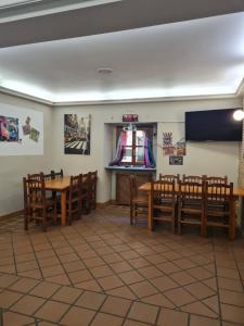 uma sala de jantar com mesas e cadeiras de madeira e um ecrã em Bar Restaurante Albergue Uncastillo em Uncastillo