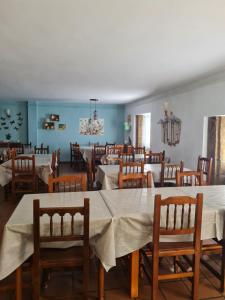 uma sala de jantar com mesas brancas e cadeiras de madeira em Bar Restaurante Albergue Uncastillo em Uncastillo