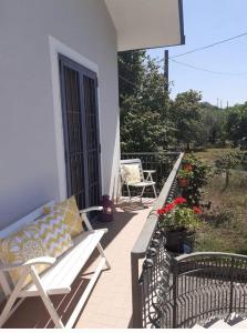 une terrasse couverte avec un banc et des chaises sur un balcon dans l'établissement Casa i Quattro Alberi, à Montemiletto