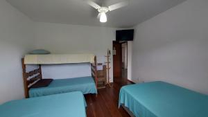 a room with two beds and a ceiling fan at Suites 500m Praia da Enseada in Guarujá