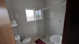 a bathroom with a shower and a toilet and a sink at Suites 500m Praia da Enseada in Guarujá