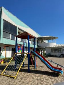 um parque infantil com um escorrega em frente a um edifício em Hotel Vila dos Pescadores em Aparecida