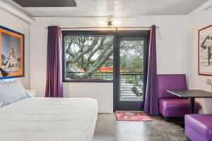 a bedroom with a bed and a window with purple curtains at Boutique Vera Hotel in the Heart of Folly Beach in Folly Beach