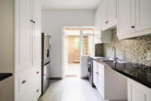 uma cozinha branca com um lavatório e um frigorífico em The Hide Out - Home away from home em Joanesburgo