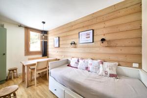een slaapkamer met een bed en een houten muur bij Résidence Plagne Lauze - maeva Home - Studio 4 personnes - Sélection 804 in Mâcot La Plagne