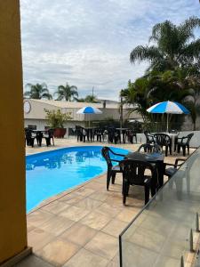 uma piscina com mesas, cadeiras e guarda-sóis em Hotel Vila dos Pescadores em Aparecida