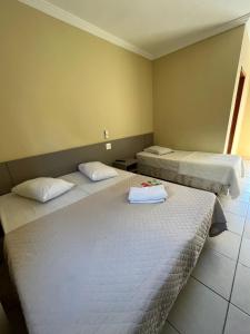 two beds in a hotel room with two bedsvisor at Hotel Vila dos Pescadores in Aparecida