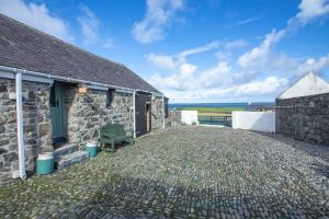 a stone cottage with a green door and a patio at Crofters Retreat 
