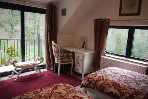a bedroom with a bed and a desk and windows at The Annexe at Riverside Cottage in Honiton
