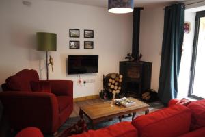 a living room with a red couch and a table at The Annexe at Riverside Cottage in Honiton