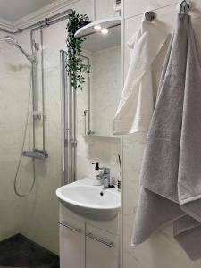 a white bathroom with a sink and a shower at Serenity Cottage 2 in Närpiö