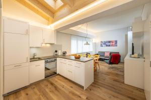 a kitchen with white cabinets and a wooden floor at Haus Rubin in Zermatt