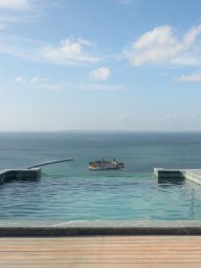 a swimming pool with a ship in the ocean at Gorges Residence Salvador in Salvador