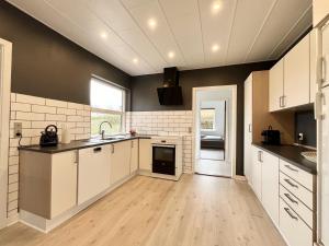a large kitchen with white cabinets and a sink at Stunning & Renovated 130sqm Villa only 5 min by car from sandy beaches in Åkirkeby
