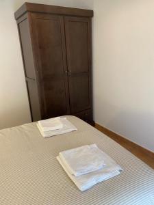 - un lit avec une commode et 2 serviettes dans l'établissement Apartamento Puerta del Perdón, à Constantina