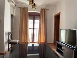 a living room with a television and a window at Apartamento Puerta del Perdón in Constantina