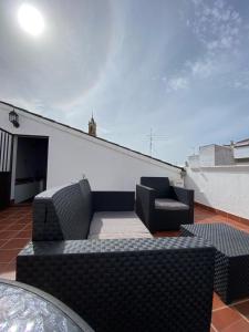 a patio with two chairs and a couch on a roof at Apartamento Puerta del Perdón in Constantina