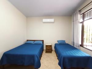 2 Betten in einem Zimmer mit blauer Bettwäsche und einem Fenster in der Unterkunft Casa de huespedes con piscina privada in Villa Tunari