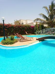 une grande piscine avec des chaises et un pont dans l'établissement Villa Savana, à La Somone