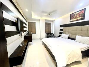 - une chambre avec un lit blanc et une télévision dans l'établissement HOTEL P PALACE ! VARANASI fully-Air-Conditioned-hotel lift-and-Parking-availability, near Kashi Vishwanath Temple, and Ganga ghat, à Varanasi