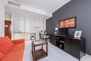 un soggiorno con divano arancione e TV di SevillaHome-Apartamento complejo piscina parking a Siviglia