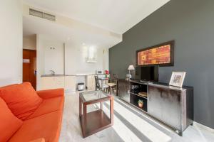 sala de estar con sofá naranja y mesa en SevillaHome-Apartamento complejo piscina parking, en Sevilla