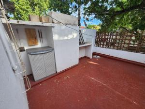 una vista exterior de un edificio blanco con suelo rojo en Casita a metros del Parque Independencia con garaje incluido en Rosario