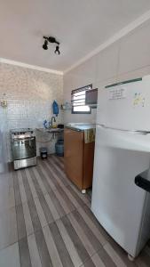 a kitchen with a white refrigerator and a counter at Suites 500m Praia da Enseada in Guarujá +6 photos