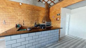 uma cozinha com uma parede de tijolos e uma bancada em Suites 500m Praia da Enseada no Guarujá