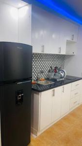 a kitchen with a black refrigerator and white cabinets at Appartamento Cristal Juan Dolio fronte mare in Juan Pedro