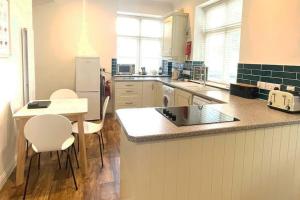 a kitchen with a counter with chairs and a table at Potters Lodge - private parking & self check in in Hornsea