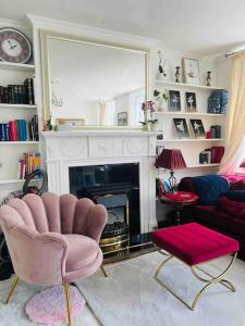 a living room with a fireplace and a pink chair at Flat in the heart of Bath with stunning views in Bath