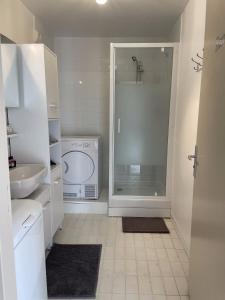 een witte badkamer met een douche en een wastafel bij F3 Cosy à Cergy à 10 minutes de la gare Cergy Préfecture et Proche ESSEC in Cergy