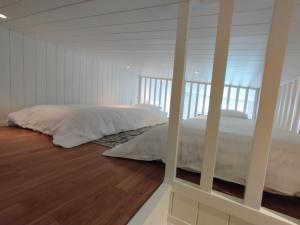 um quarto com uma cama com lençóis brancos e pisos em madeira em Bålsta Studio Houses em Bålsta